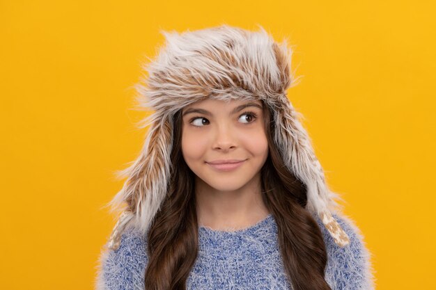 Una jovencita feliz usa un sombrero con orejeras sobre fondo amarillo, Retrato