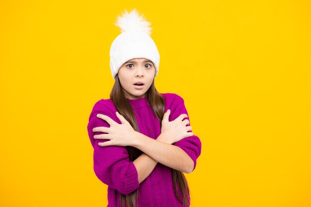 Jovencita moderna con suéter y gorro de punto sobre fondo amarillo aislado Enojada adolescente disgustada e infeliz emoción negativa