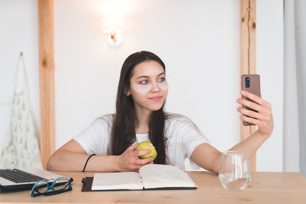 Jovencita con parches en los ojos mirar la pantalla del teléfono inteligente