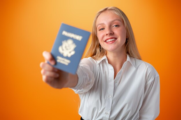 Jovencita con pasaporte para viajar con fondo naranja