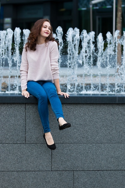 Jovencita posando en una fuente de agua