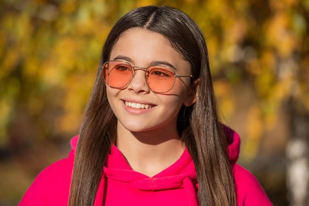 Jovencita positiva al aire libre en la temporada de otoño con gafas de sol