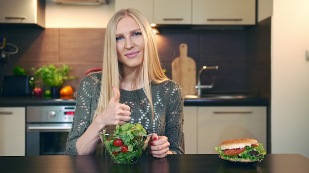 Jovencita prefiriendo ensalada a hamburguesa.