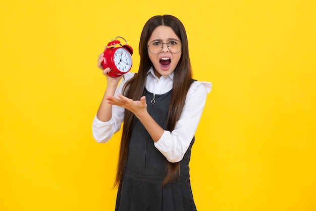 Jovencita puntual comprobando el tiempo Niño con reloj despertador mostrando la hora