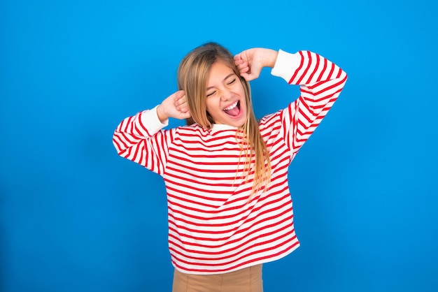 Jovencita relajándose y estirando los brazos y las manos detrás de la cabeza y el cuello sonriendo feliz