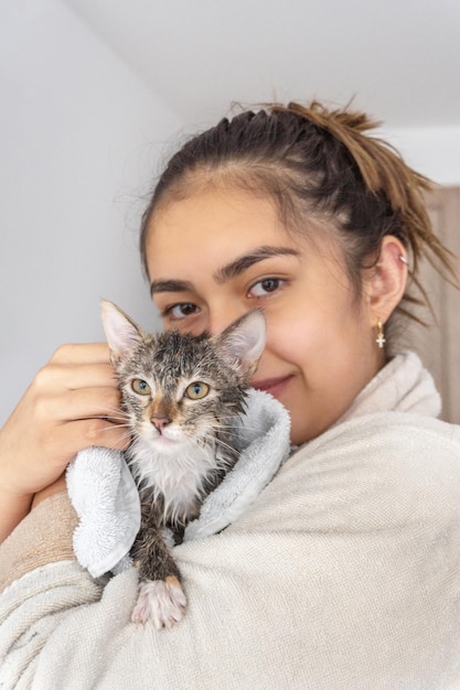 Jovencita secando un gato bañado con una toalla