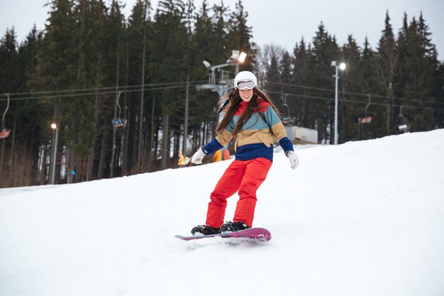 Jovencita snowboarder en las laderas día de invierno helado