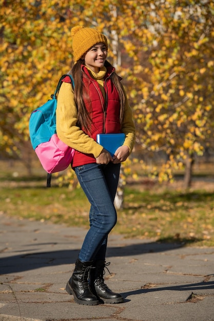 Una jovencita sonríe de regreso a la escuela en otoño de longitud completa