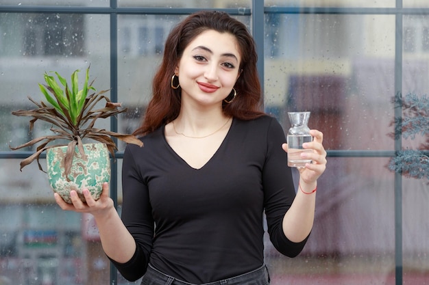 Jovencita sonriente sosteniendo maceta y agua Foto de alta calidad