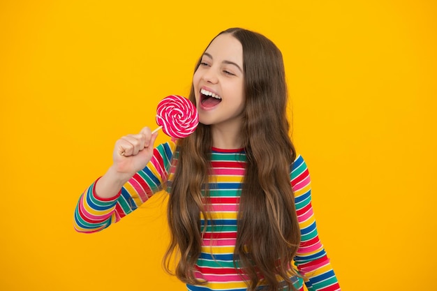 Foto jovencita sostenga piruleta de caramelo sobre fondo amarillo tienda de dulces