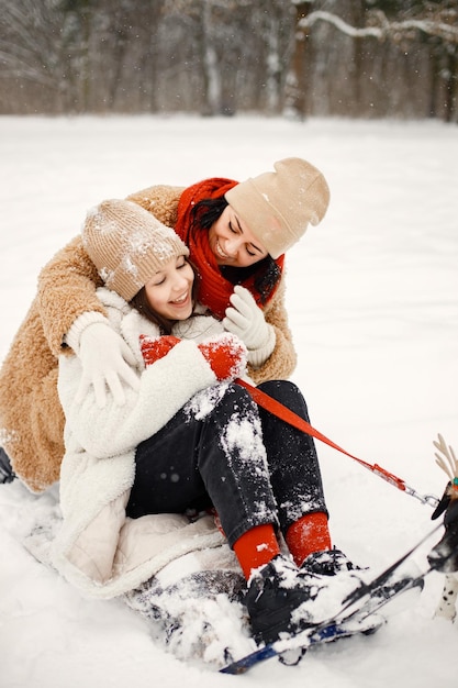 Jovencita y su madre montando un trineo en el parque de invierno