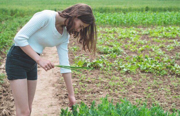 Jovencita toca las manos con plantas verdes en el jardín