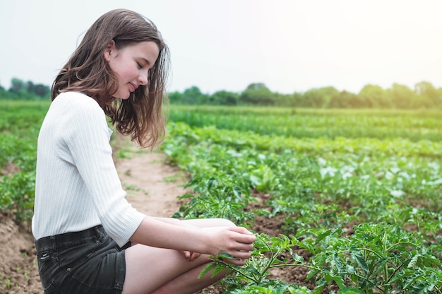 Jovencita toca las manos con plantas verdes en el jardín