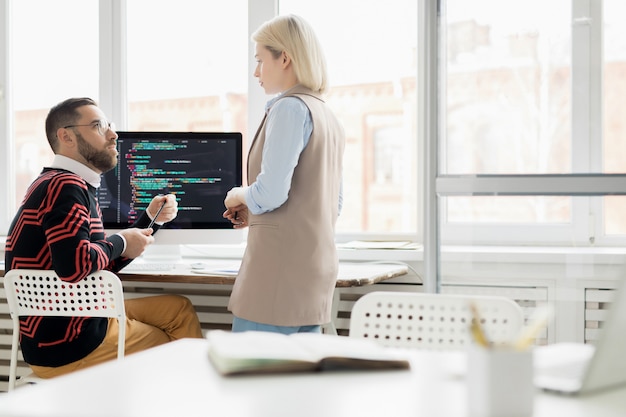 Jovencita trabajando con programador en oficina