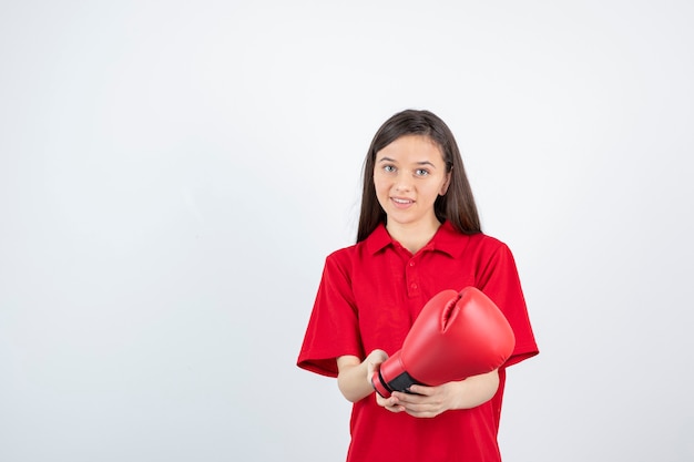 Jovencita en uniforme rojo sosteniendo un guante de boxeo