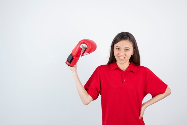 Jovencita en uniforme rojo sosteniendo un guante de boxeo