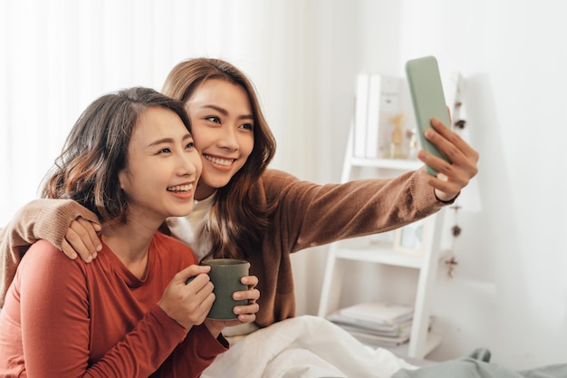 Jovencitas asiáticas haciendo selfie en la cama