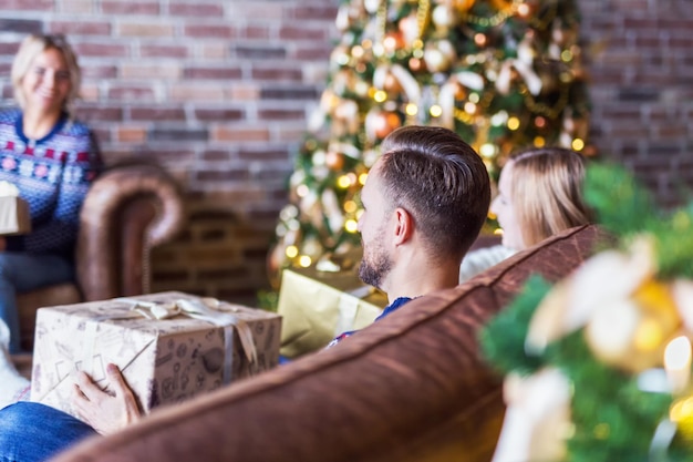 Los jóvenes abriendo cajas de regalo de navidad por un árbol de navidad