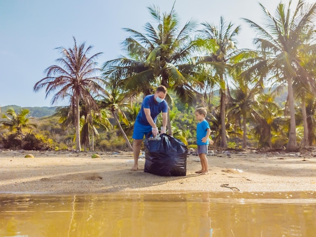 Jóvenes activistas familiares felices recogiendo desechos plásticos en la playa Papá e hijo voluntarios limpian basura Problemas de contaminación ambiental Recreación al aire libre Educación natural de los niños