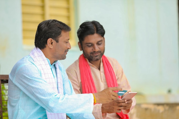 Jóvenes agricultores indios con tarjeta de crédito o débito con smartphone en casa