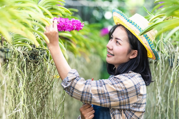 Jóvenes agricultores mujeres caminando para comprobar la orquídea jardinería mujer de la granja comprobar la calidad de la flor de orquídea en el invernadero del jardín conceptos agrícolas