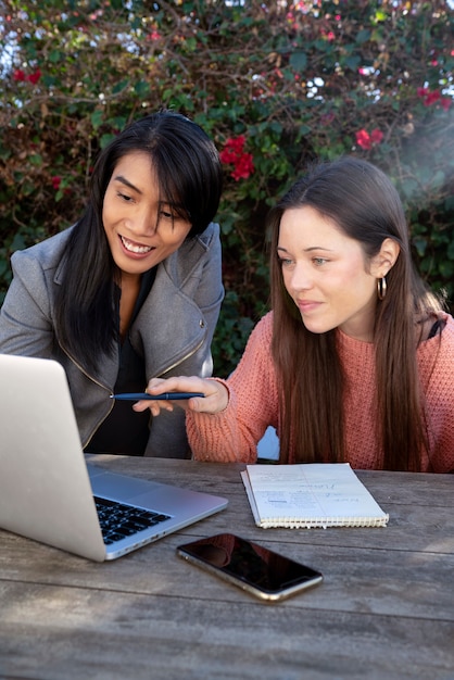 Jóvenes amigas usando laptop juntas al aire libre