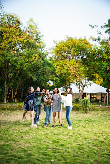 Jóvenes amigos asiáticos indios jugando fútbol, fútbol o voleibol y animando