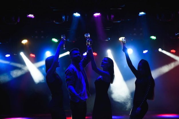 Foto jóvenes amigos bailando con copas de champagne en las manos.