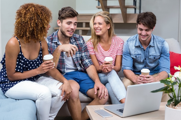 Jóvenes amigos con bebidas sentado en el sofá