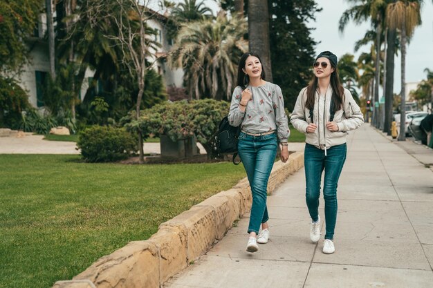 jóvenes amigos bonitos caminando por la acera y hablando alegremente mientras tienen una cita relajante.