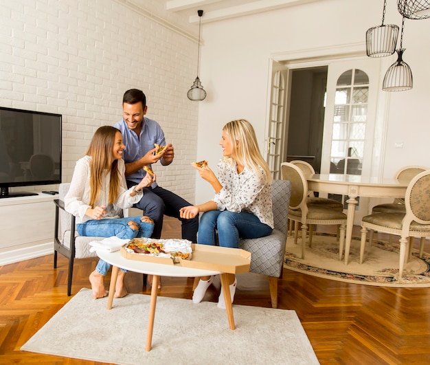 Jóvenes amigos comiendo pizza en la habitación.