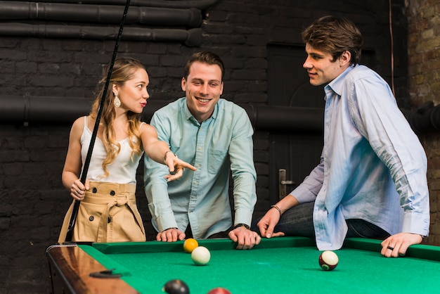 Foto jóvenes amigos conversando mientras juegan billar en el club