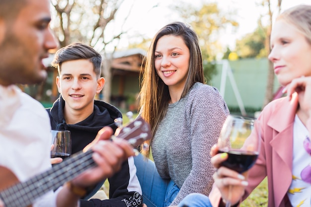 Jóvenes amigos disfrutando de la música de guitarra al aire libre