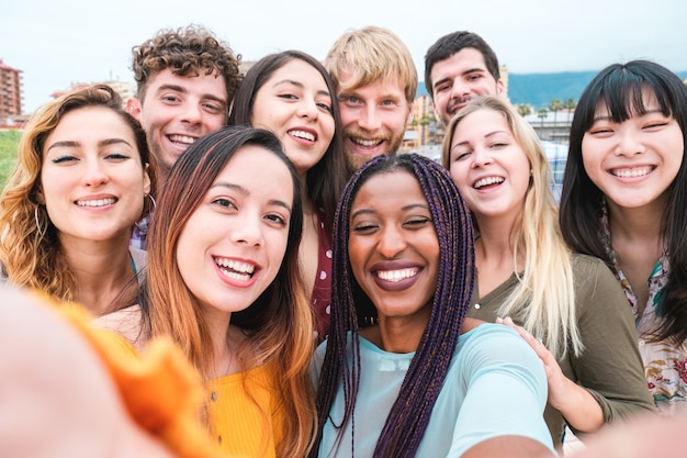 Jóvenes amigos de diversas culturas y razas tomando fotos, haciendo caras felices