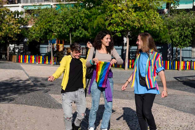 Foto jóvenes amigos diversos caminando por la calle con la bandera del arco iris lgbt