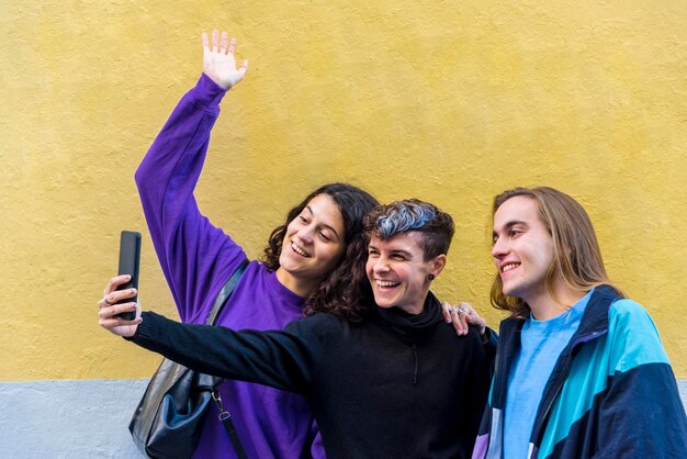 Jóvenes amigos diversos tomando selfies con un teléfono móvil al aire libre