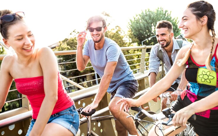 Jóvenes amigos divirtiéndose montando en bicicleta en el parque de la ciudad