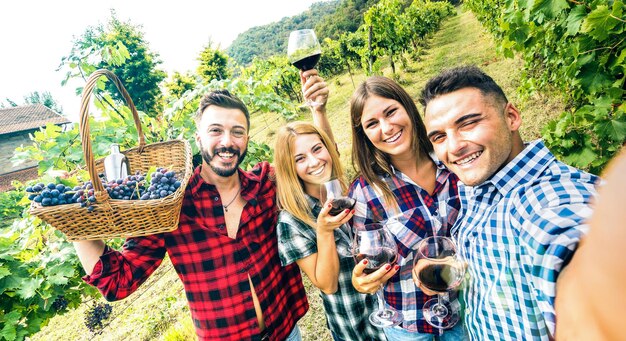 Jóvenes amigos divirtiéndose tomando selfie en el viñedo de la bodega al aire libre