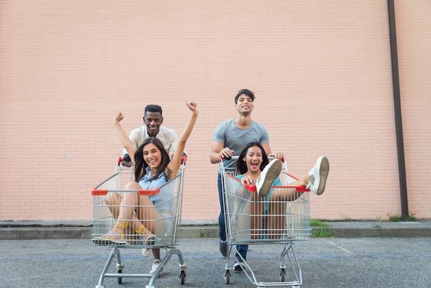 Jóvenes amigos felices corriendo con carritos de compras