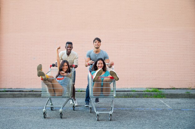 Jóvenes amigos felices corriendo con carritos de compras