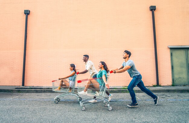 Jóvenes amigos felices corriendo con carritos de compras