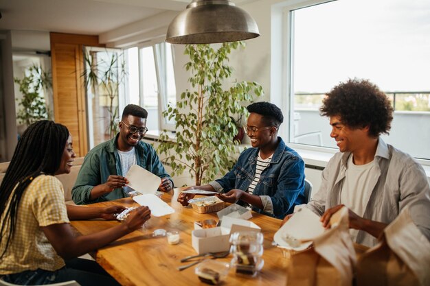 Jóvenes amigos felices divirtiéndose durante el almuerzo en casa