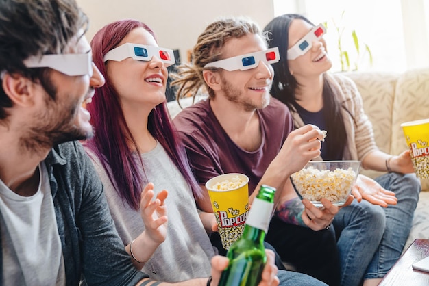 Jóvenes amigos felices con gafas 3D viendo películas en casa