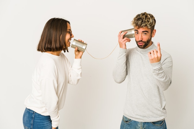 Foto jóvenes amigos hispanos hablando a través de un sistema de lata apuntando con el dedo hacia usted como invitando a acercarse