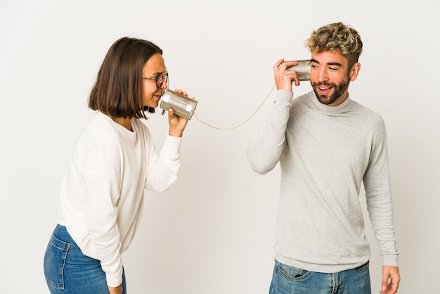 Jóvenes amigos hispanos hablando a través de un sistema de latas miran a un lado sonrientes, alegres y agradables.