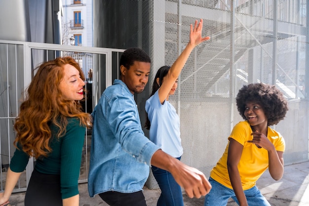 Jóvenes amigos multiétnicos bailando en la ciudad diversión milenaria con música