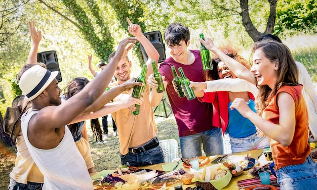 Foto jóvenes amigos multirraciales brindando cerveza en la fiesta en el jardín de barbacoa