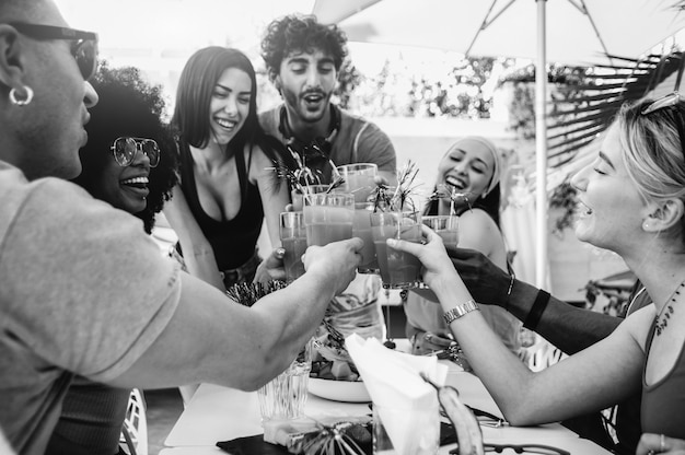 Jóvenes amigos multirraciales brindando cerveza en la fiesta en el jardín de barbacoa