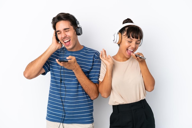 Jóvenes amigos de raza mixta aislados sobre fondo blanco escuchando música con un móvil y cantando