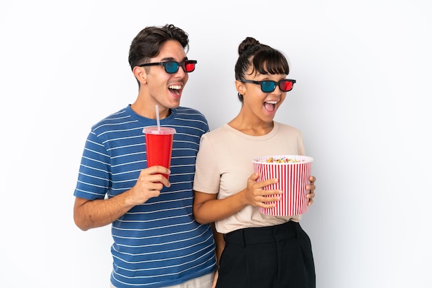 Jóvenes amigos de raza mixta aislados sobre fondo blanco con gafas 3d y sosteniendo un gran balde de palomitas de maíz